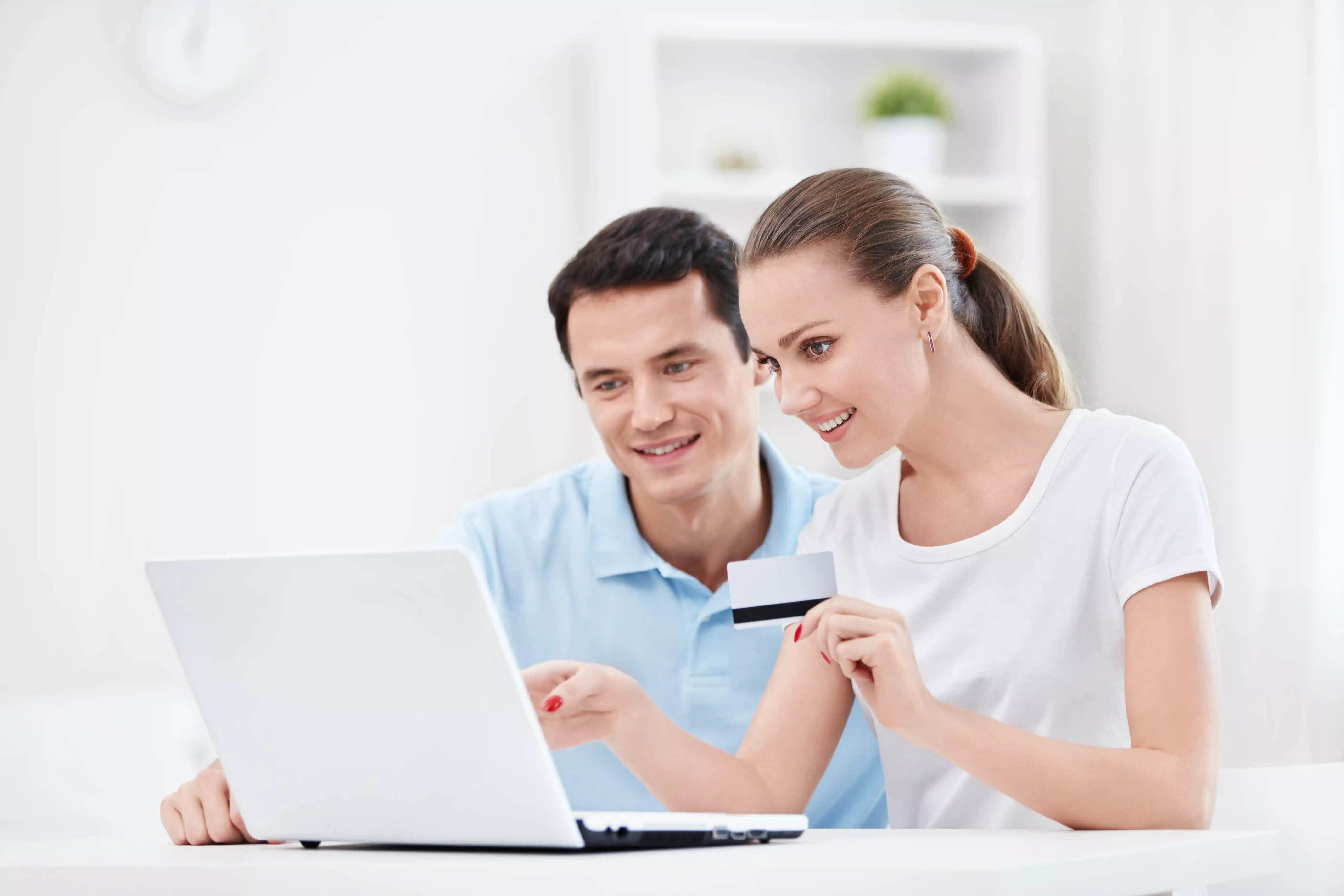 couple holding a credit card in front of a laptop