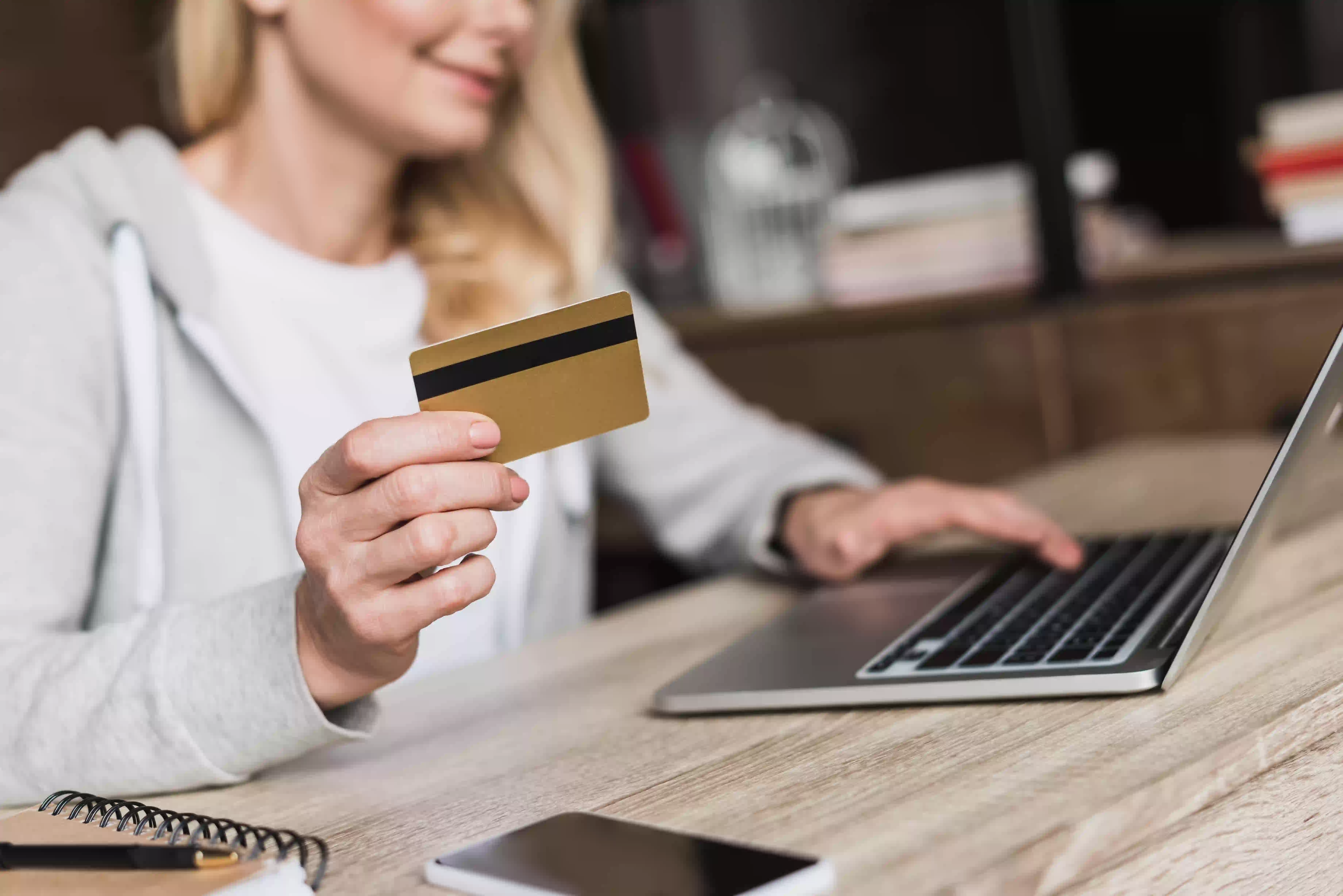 woman holding credit card in front of laptop