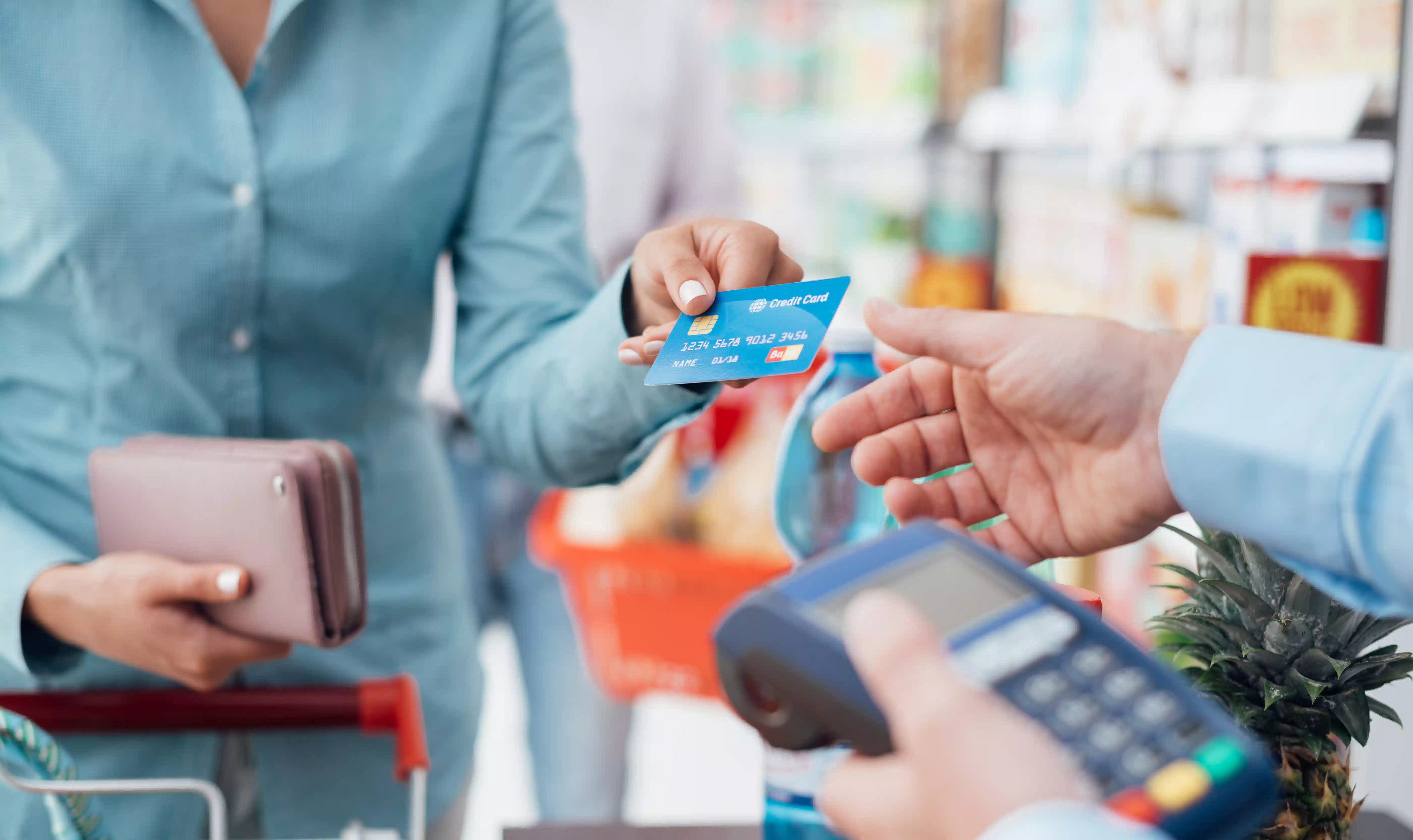 woman in the grocery handing her credit card in the cashier