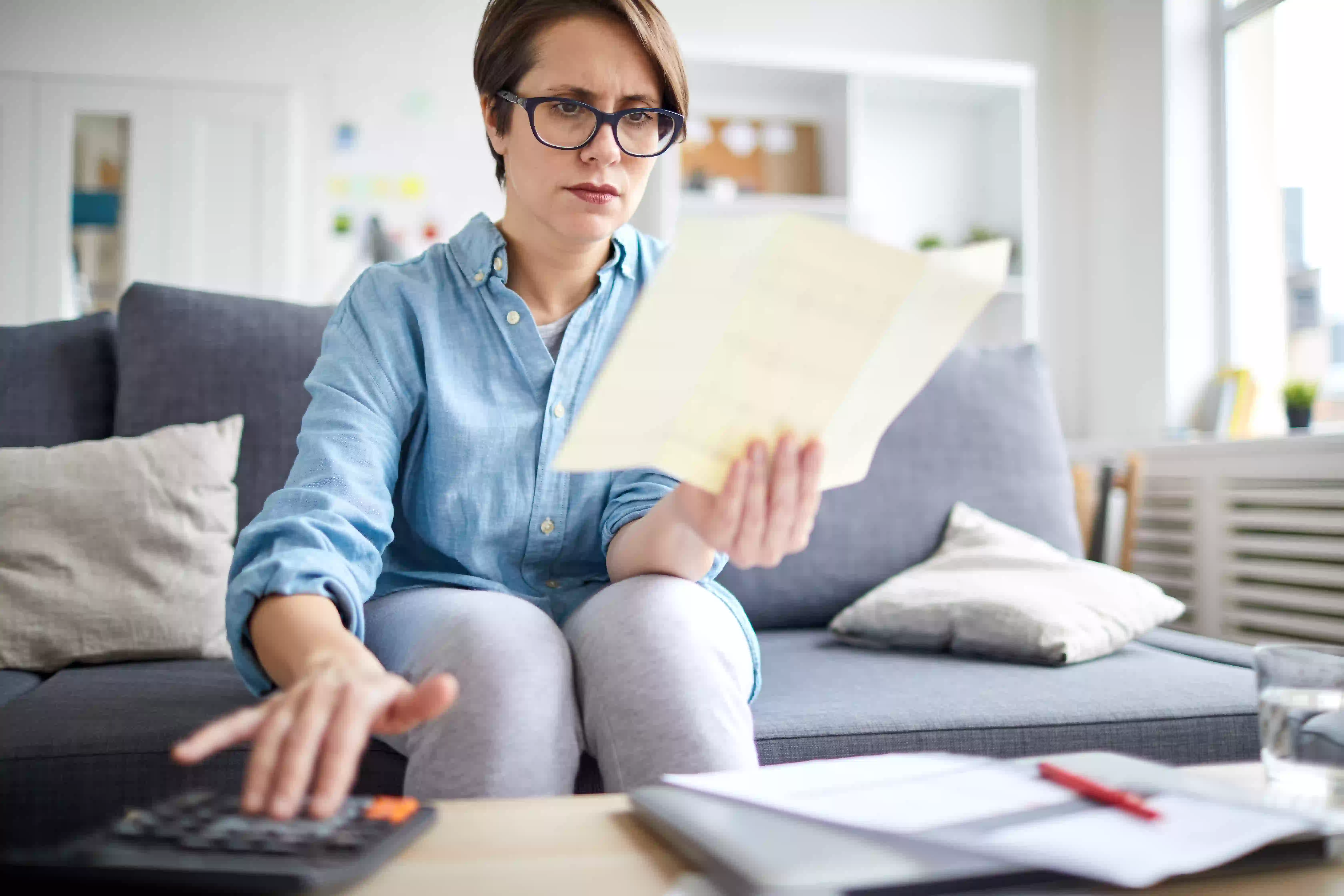 woman calculating while holding and reading paper