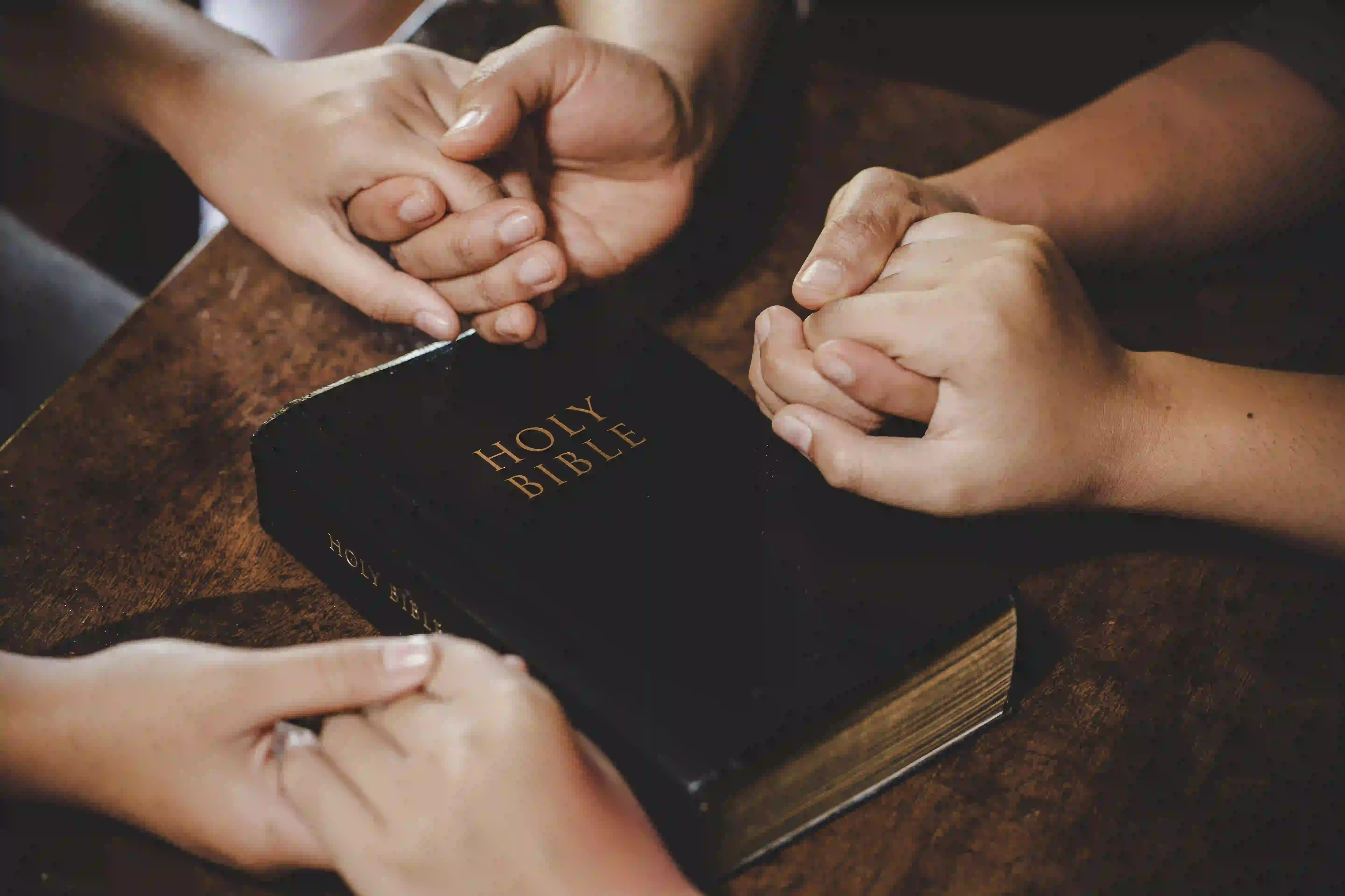 people holding hands around the Bible