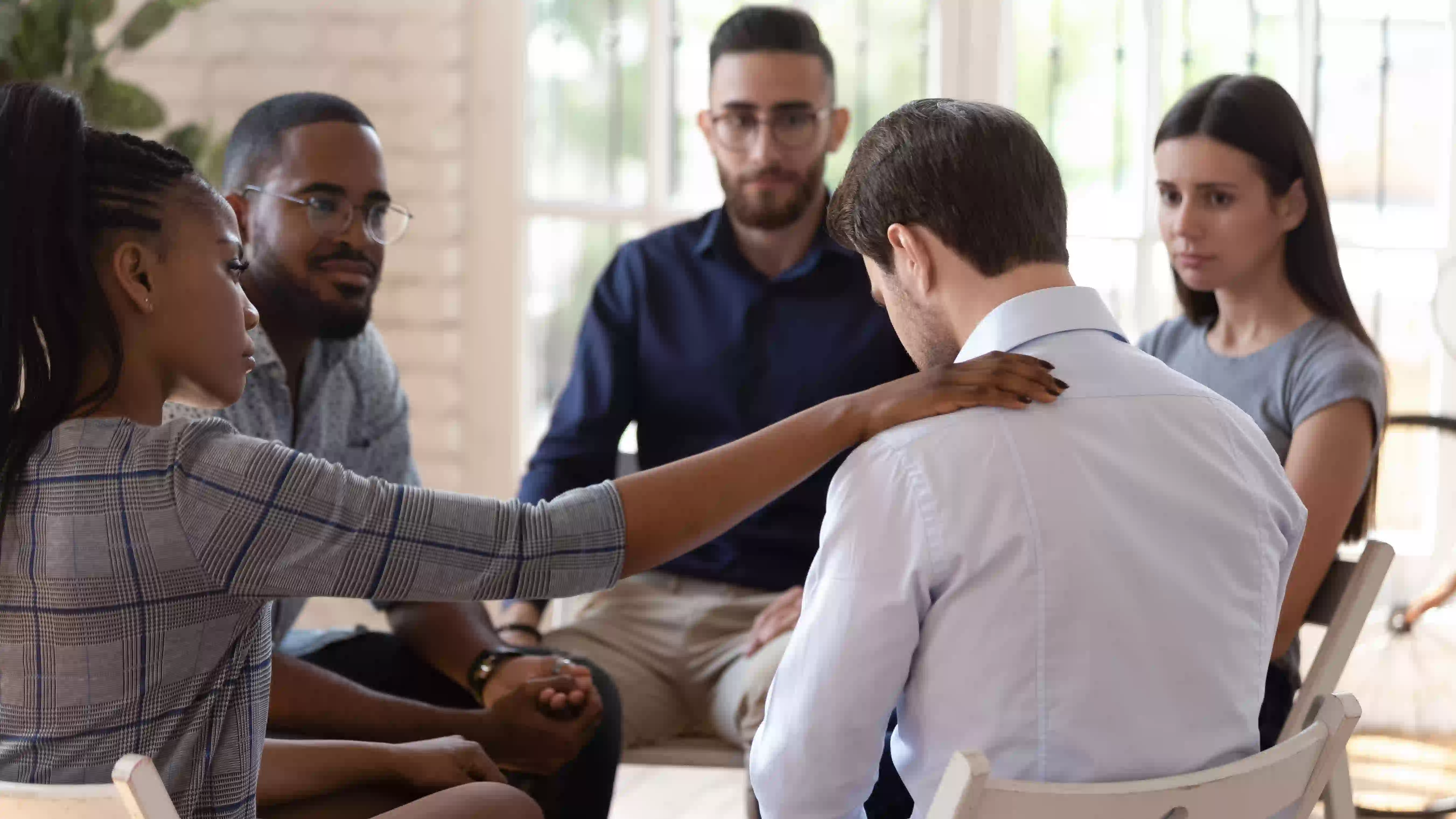 people sitting in a circle comforting a man