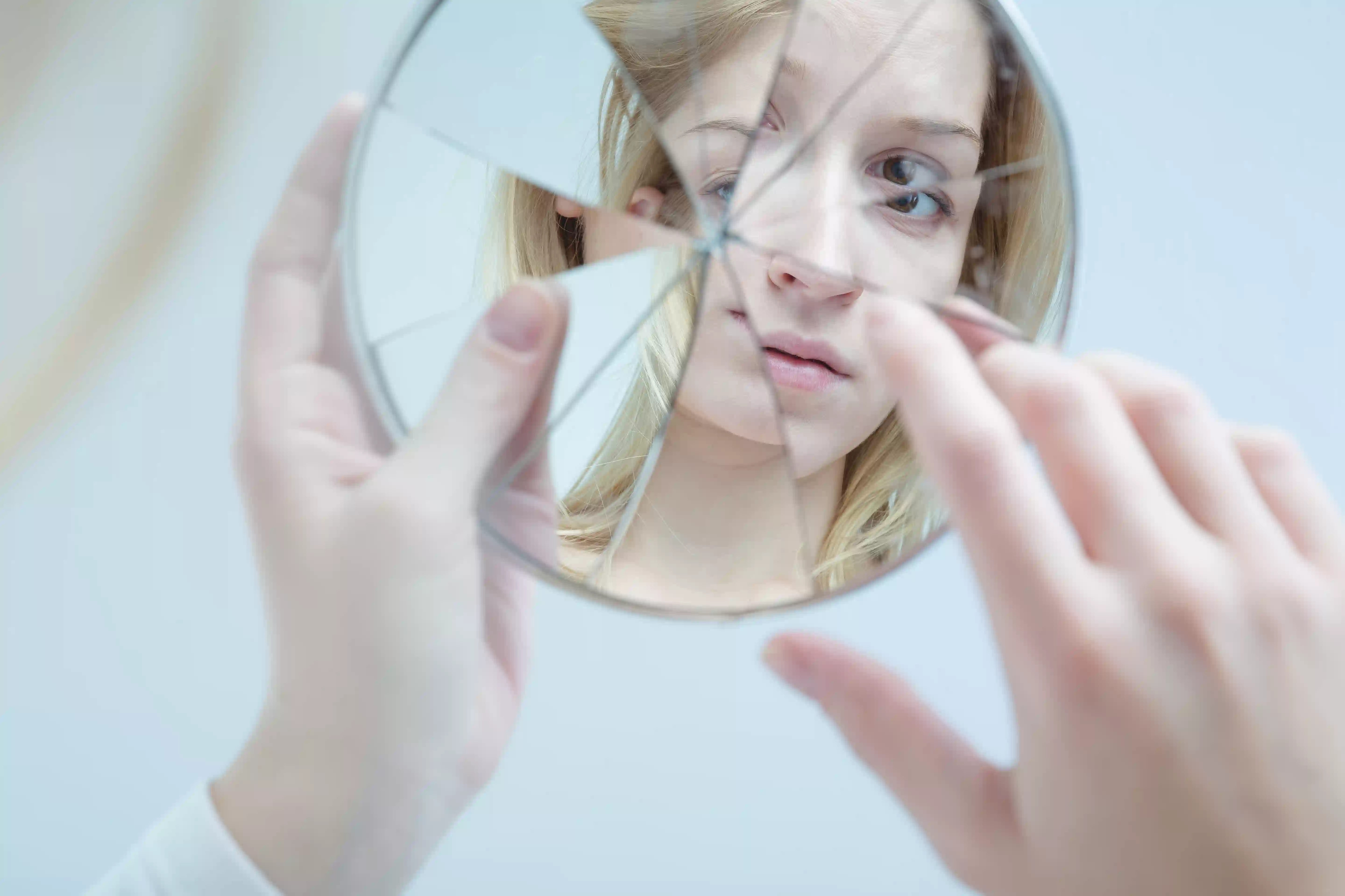 woman watching her face in a broken mirror