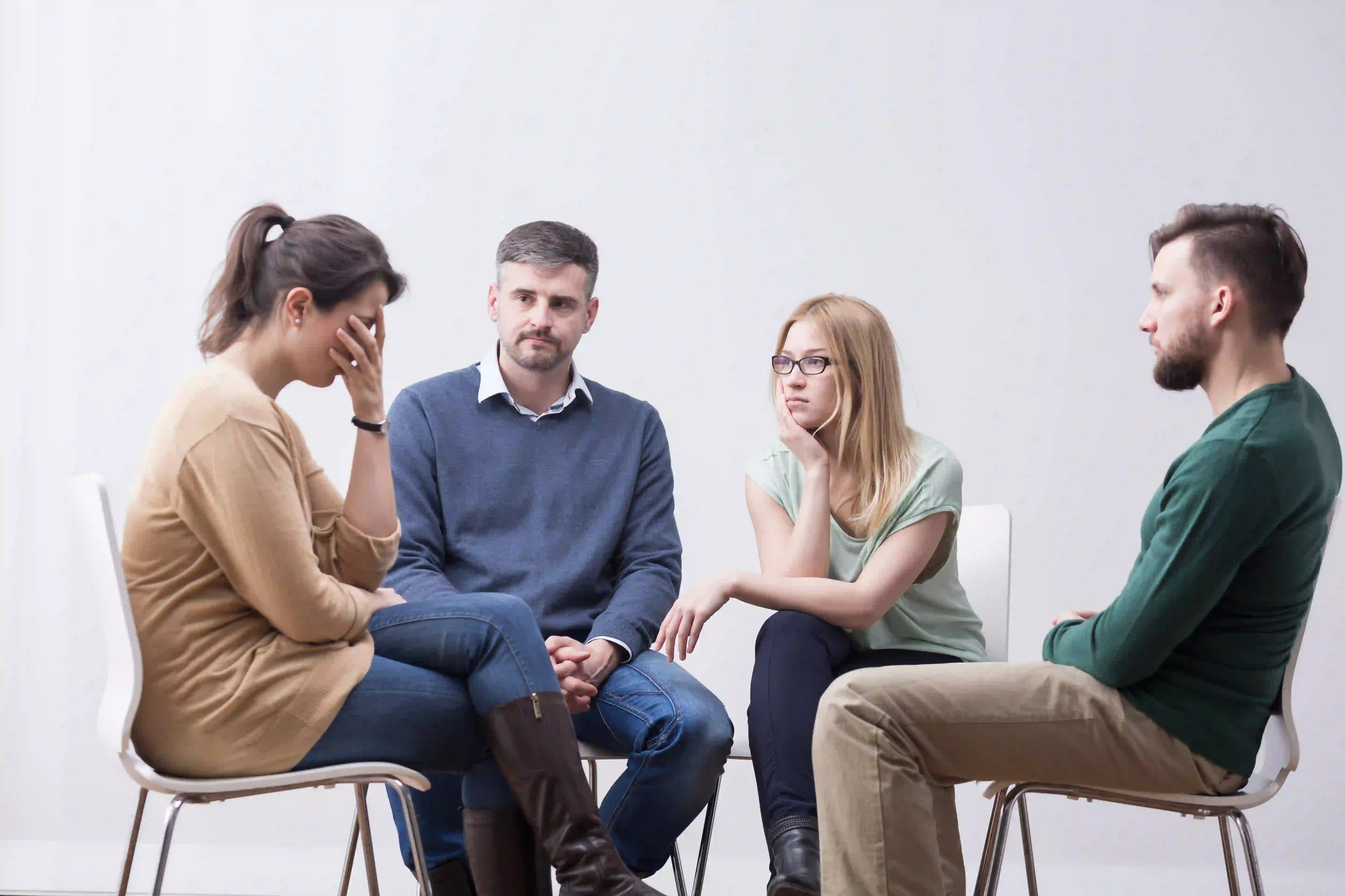 middle age people sitting in a circle comforting a woman in a group setting