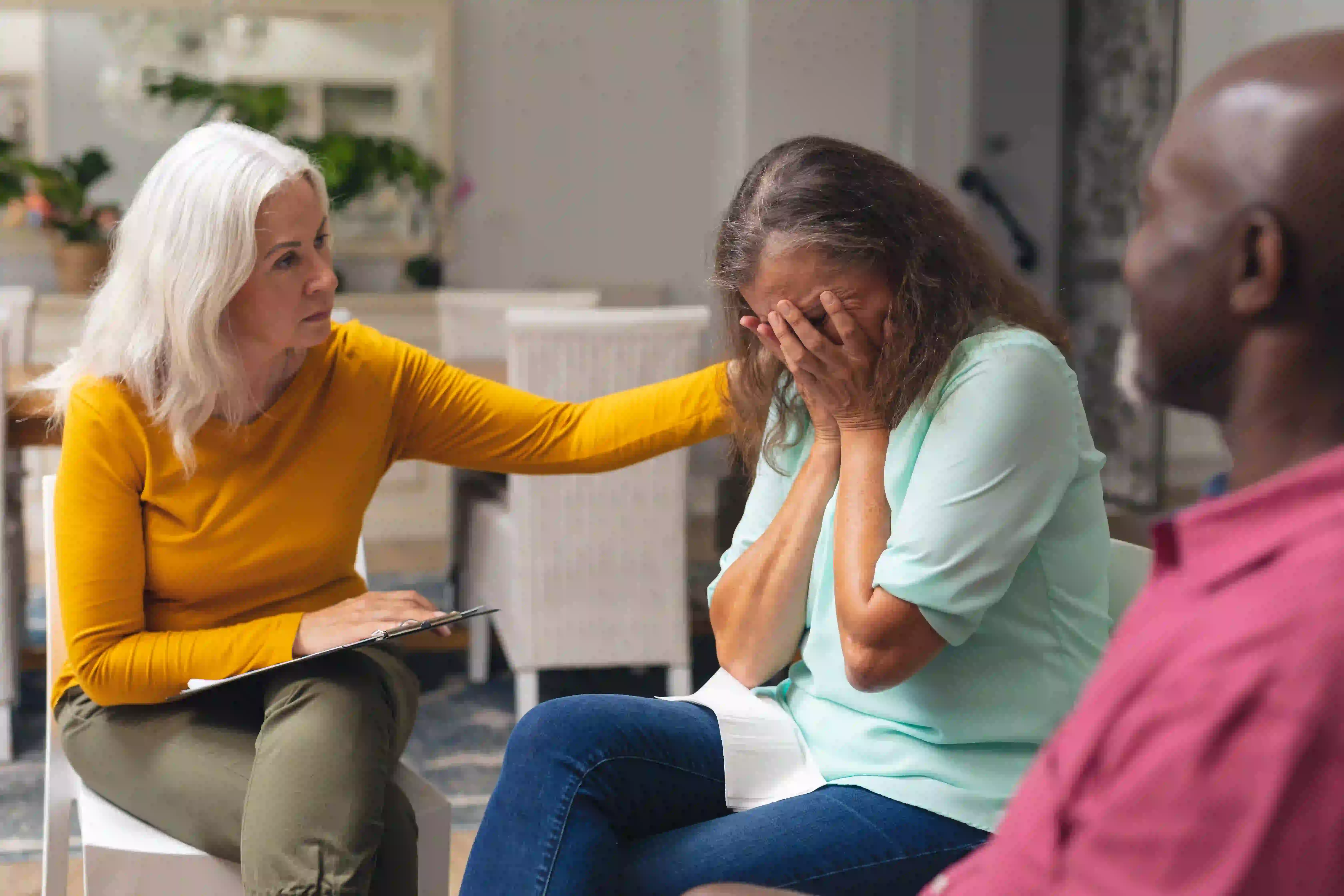 woman comforting another woman in a group with man